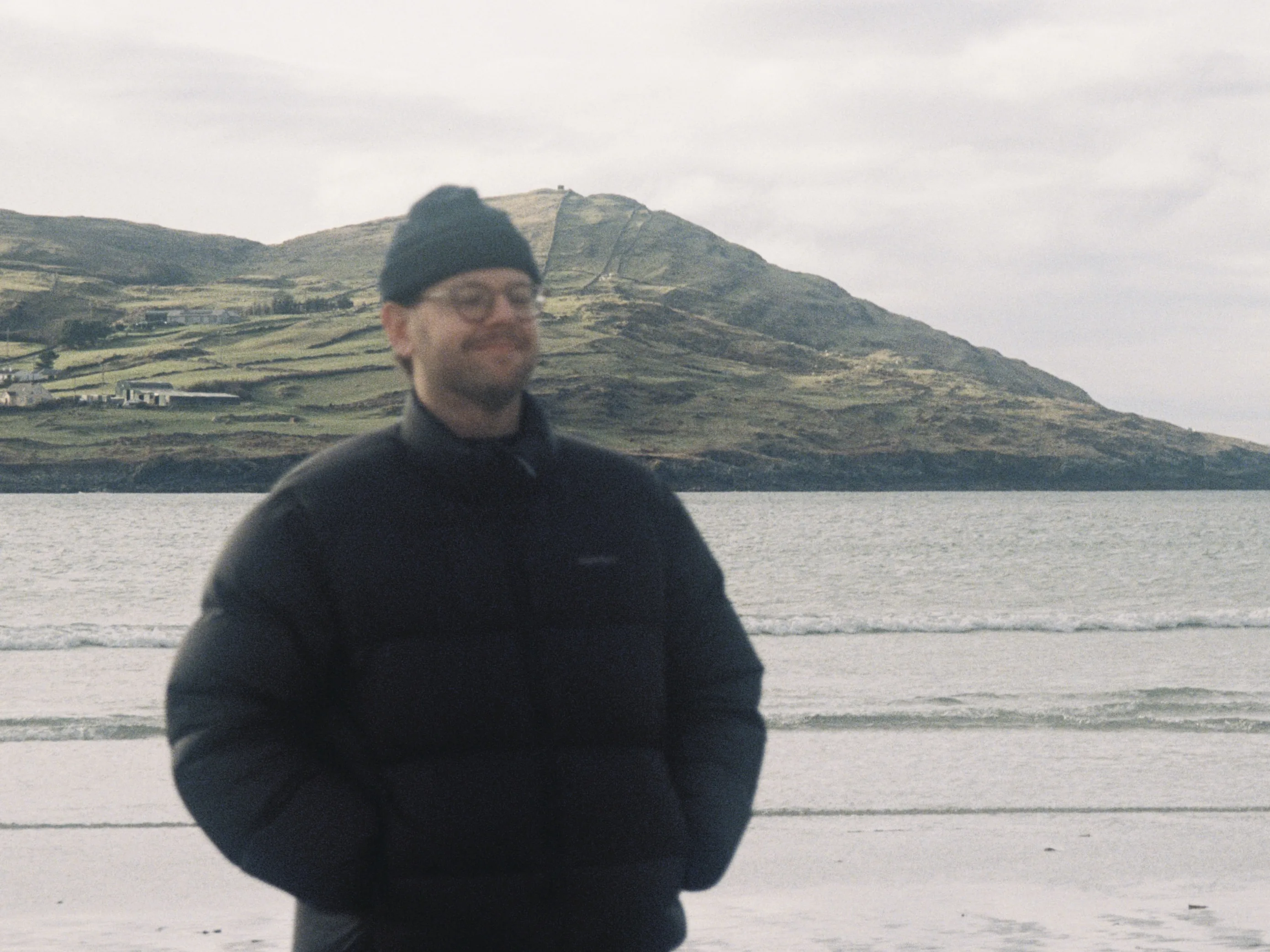 Aaron Gilmore standing on a beach with a mountain in the background